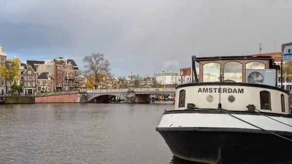 De Blauwbrug met op de voorgrond een woonboot met de naam Amsterdam.