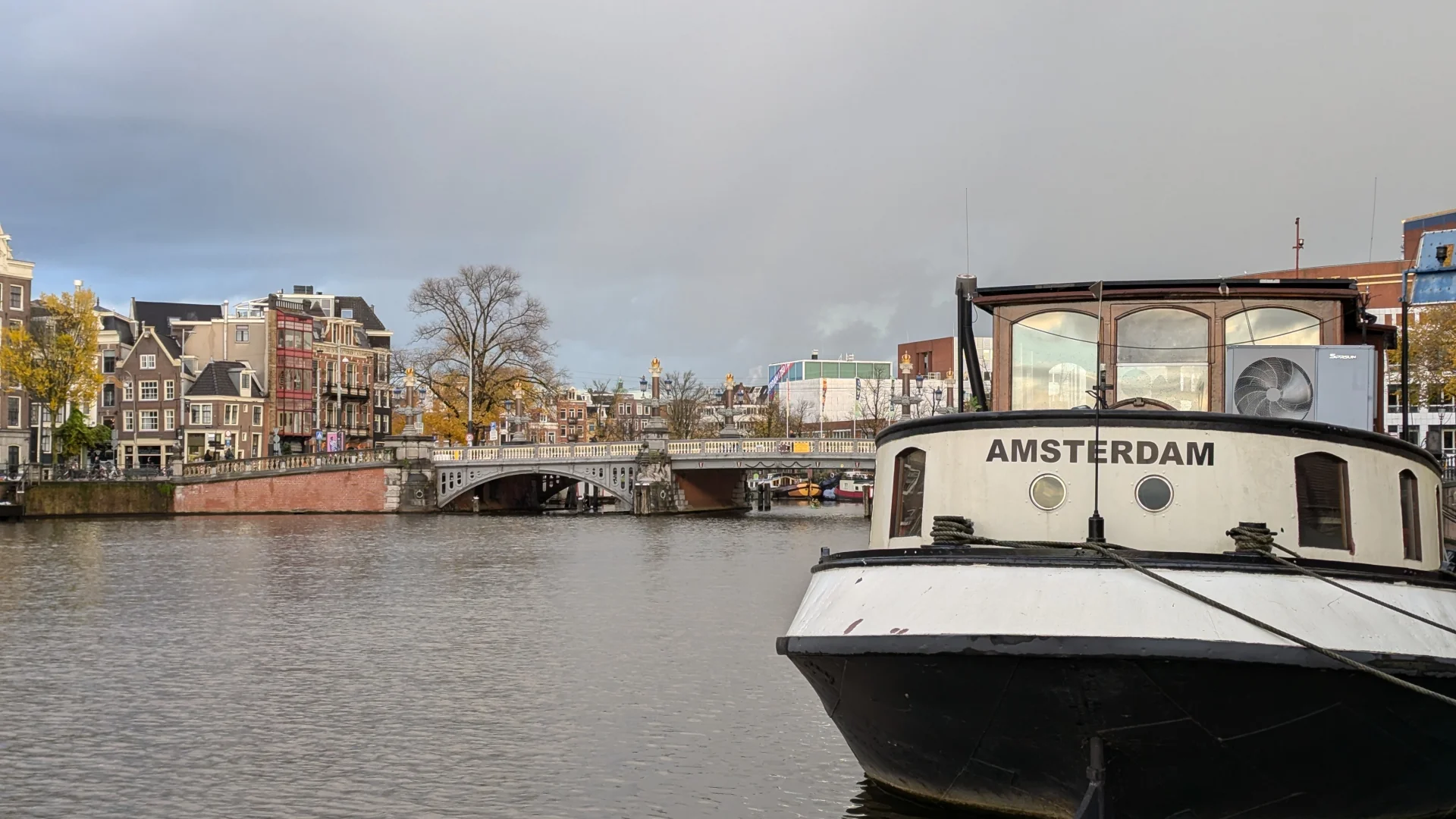 De Blauwbrug met op de voorgrond een woonboot met de naam Amsterdam.